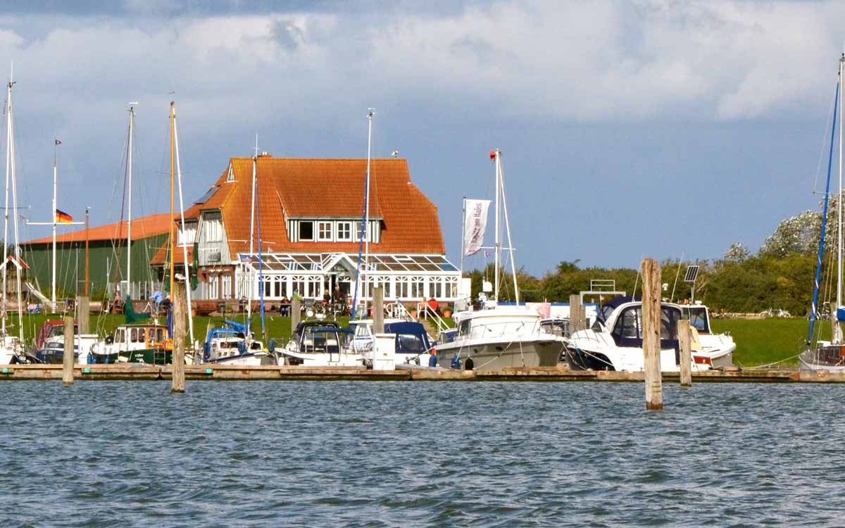 Yachthafen von Langeoog mit Booten und einem Deich mit Restaurant